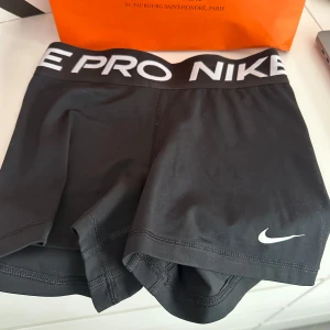 Svarta träningsshorts från Nike - Snygga svarta Nike Pro träningsshorts med Dri-FIT-teknologi för optimal komfort. De har en elastisk midja med Nike-logga och är perfekta för intensiva träningspass. Shortsen är designade för att sitta tight och ge stöd under träning.