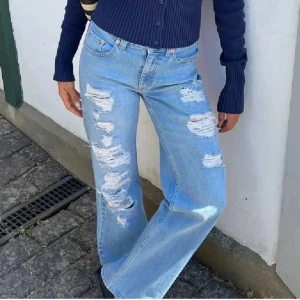 Ljusa jeans med slitningar - Snygga ljusblå jeans med slitningar på benen. De har en avslappnad passform och är perfekta för en trendig look. Kombinera med en stickad tröja eller en blus för en stilren outfit.