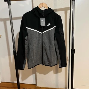 Nike-tech hoodie - Helt ny och oanvänd Nike tech hoodie. 10/10 skick. Det står storlek L men den sitter som en S. Riktigt fin och bekväm. Rekommenderar starkt!