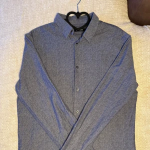 Blå skjorta från J.Lindeberg - Snygg blå skjorta från J.Lindeberg i storlek M. Skjortan har långa ärmar och knappar framtill. Perfekt för en stilren look.