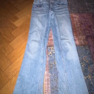 Blå bootcut jeans från H&M - Säljer ett par snygga blå bootcut jeans från H&M i storlek 152. De har låg midja och justerbar midja för perfekt passform. Perfekta för en avslappnad stil.