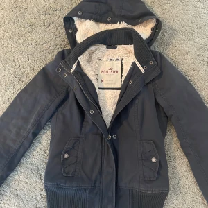 Vintage mörkblå Hollister jacka - Säljer denna supersnygga jackan från Hollister som är i bra skick! Det enda felet är att den har en tråddragning på ena ärmen, (kan ses på bild 4). Den är liten i storleken och passar en strl S! Svår att få tag i någon annanstans, skriv vid frågor☺️