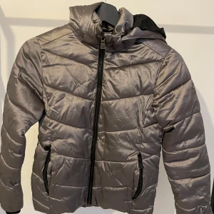 Pufferjacka från McKinley - En vinterjacka med avtagbar huva. Se bild nummer 3 för ett litet ihopsytt ”hål” (därav priset), annars är jackan felfri och har mycket kvar att ge
