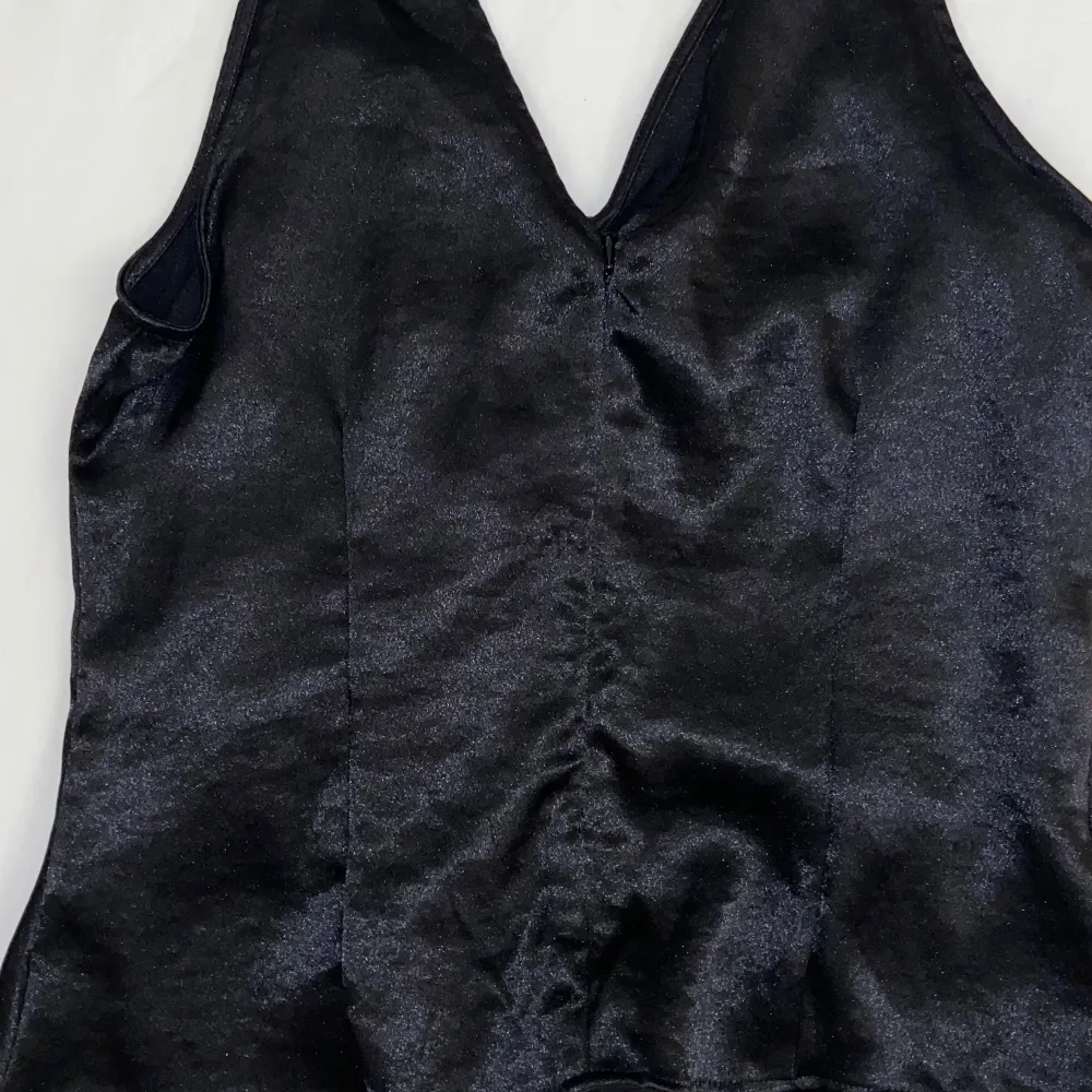 Säljer en snygg svart glittrig topp från H&M i storlek M. Toppen har en åtsittande passform och är perfekt för festliga tillfällen. Den har en elegant rynkad detalj på baksidan som ger en extra touch. Perfekt för att glittra på festen! ✨. Puserot.