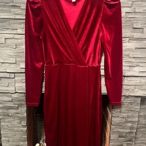 Röd sammetsklänning från ONLY - Säljer en superfin röd sammetsklänning från ONLY i storlek S. Klänningen har en omlott-design med långa ärmar och en elegant v-ringning. Perfekt för höst- och vinterfester! 💃