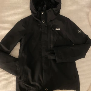 Svart jacka från Dope - Säljer en svart skidjacka från Dope i mycket bra skick. Den har en dragkedja och är långärmad med en snygg och stilren design. Perfekt för höst och vinter med sitt varma material. Jackan har en normal passform och är idealisk för både vardag och utomhusaktiviteter. Olika funktionella fickor och ”bälte ” i midjan på insidan, vilket förhindrar vind och snö att komma in. Går bra att trä luvan över hjälmen om man vill det! 2000kr nypris. Skriv för minsta fundering😊
