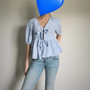 Fin blus med knytning - Säljer en söt ljusblå blus med knytning framtill. Den har trekvartsärmar och en volangdetalj som ger en super söt  touch. Perfekt för vår och sommar! Kan stylas me allt!  💙