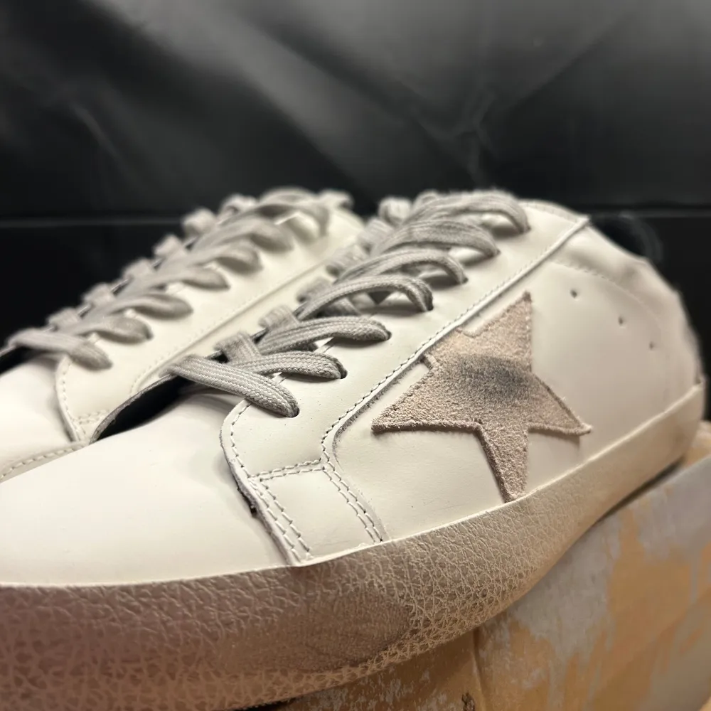 Säljer ett par stilrena vita golden goose från GGDB med en snygg stjärndetalj på sidan. 🌟🤩Skorna har en klassisk design med snörning och en svart häl. Perfekta för både vardag och fest!Kan funka som vinterskor med. De är i mycket bra skick och kommer med originalförpackning. 🍾✨ Använda endast ett fåtal gånger sparsamt. Hör av dig - Emil 🤙🤙. Skor.