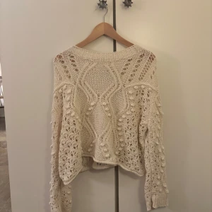 Beige stickad tröja med hålmönster - Superfin beige stickad tröja från Zara med ett unikt hålmönster. Den har en loose passform och långa ärmar, perfekt för höst och vår. Tröjan är både mysig och stilren, vilket gör den idealisk för både vardag och fest.