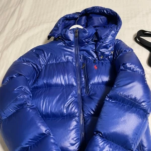 Blå dunjacka från Polo Ralph Lauren - Säljer denna sjukt snygga blå Ralph lauren jacka i mycket bra skick och är perfekt för nu kommande vinter. (Ny pris 6099) Har använt ett få tal gånger med inget fel med jackan. Dm för frågor och pris kan diskuteras! 