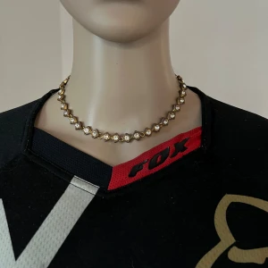 Guldigt halsband med vita stenar - Missfärgat på flera ställen.