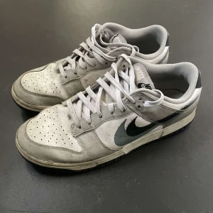 Grå Nike Dunk sneakers - Säljer ett par grå Nike Dunk i dåligt skick. Skorna på insidan är inget fel på men är väldigt smutsiga och har sina defekter, dem e väl använde där av priset skriv vid frågor de är i storlek 42 om jag inte minns helt fel.