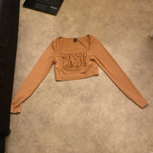 Beige ribbad topp från Shein - Säljer en superfin beige ribbad topp från Shein i storlek M. Den har långa ärmar och en snygg croppad design med rynkdetaljer framtill. Perfekt för både vardag och fest! 🧡