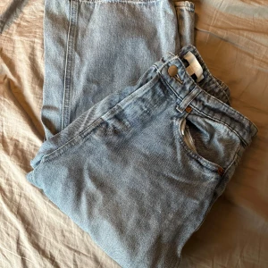 Ljusblå jeansbyxor - Säljer ett par ljusblå jeansbyxor i bra skick. De har en klassisk design med knappar och en bekväm passform. Perfekta för vardagsbruk och kan matchas med nästan vad som helst. Passar både vår och sommar!