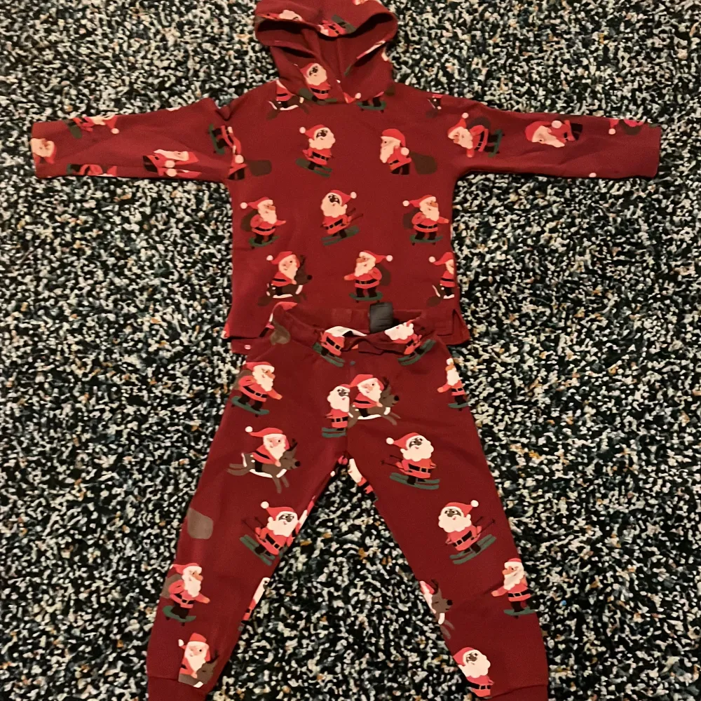 Supermysig röd pyjamas med tomtemönster, perfekt för julen! Setet består av en hoodie och matchande byxor. Materialet är mjukt och skönt. Har aldrig använts och har inga skador. Köptes för 250 men säljs för 150kr  . Tröjor & Koftor.