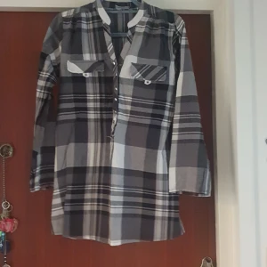 Rutig långärmad skjorta från Opus - Säljer en superfin rutig skjorta i grå och svart. Den har långa ärmar och knappar framtill. Perfekt för höst och vår, och funkar både till vardags och fest. Skjortan har två bröstfickor med knappar som ger en cool look. Passar perfekt till jeans eller leggings!