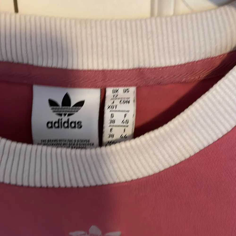 Säljer en snygg rosa långärmad tröja från Adidas med de klassiska vita ränderna längs ärmarna. Tröjan har en vit ribbad krage och är perfekt för en sportig look. Den är i bra skick och passar perfekt till både vardag och träning. 🌸. T-shirts.