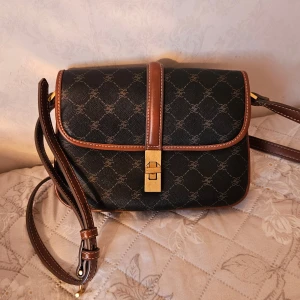 Axelremsväska från Mango - Mangoväska. Använt fåtal gånger och är i bra skick. Finns en liten defekt under väskan, se bild. Köpt för 599 kr   Material: skinnimitation  Innerfoder: polyester  Höjd: 7 cm Längd: 23 cm  Vidd: 6 cm