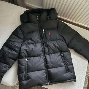 Svart Polo Ralph Lauren Jacka - Säljer en svart Polo jacka i nyskick. Den är perfekt för vintern med sin varma och quiltade design. Pris går att diskuteras! Den är i storlek M, men passar även S