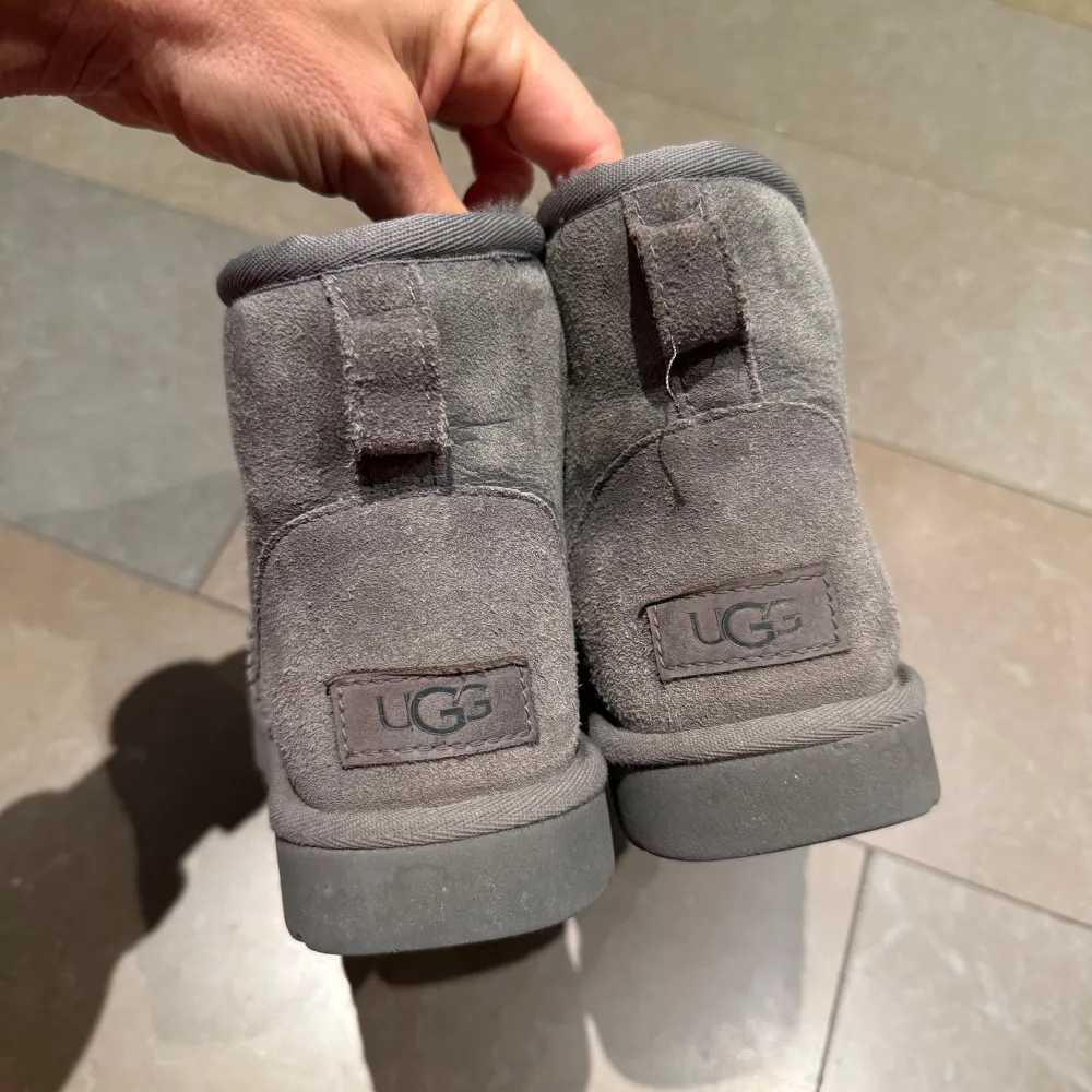 Säljer ett par grå UGG boots i bra skick. De är supermysiga med mjukt foder inuti och perfekt för kalla dagar. Tillverkade i mocka med en robust sula som ger bra grepp. Perfekta för höst och vinter!. Skor.