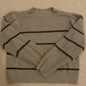 Beige stickad tröja med svarta ränder Passar för hösten !  - Säljer en mysig beige stickad tröja med svarta ränder. Perfekt för kyliga dagar med sin varma och bekväma passform. Tröjan har långa ärmar och en klassisk rund halsringning. Passar både till vardags och lite finare tillfällen. 🧶