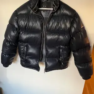 Säljer en snygg svart pufferjacka i storlek S från Armani Exchange. Jackan är i bra skick och perfekt för kalla dagar. Den har en dragkedja framtill och är quiltad för extra värme. Passar perfekt för både höst och vinter.