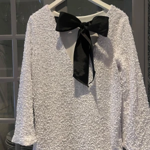 Jul/nyårs klänning  - Superfin och populär vit klänning med en svart rosett i nacken. Endast använd en gång så super bra skick!! 