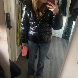  virala nelly jackan - En snygg svart pufferjacka från Nelly. Den är glansig och har en dragkedja framtill. Jackan har en huva. Storlek S passar nog Xss-M, helt skutsåld online