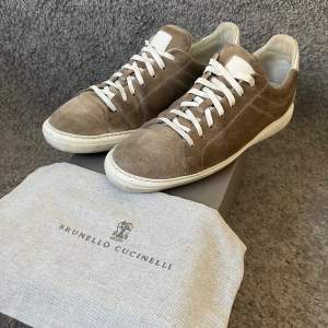 Säljer ett par snygga Brunello Cucinelli sneakers i beige mocka med vita snören och detaljer | Skick 8,5/10| Nypris ligger på runt 10.000kr | Storlek 45-28cm i innersula |Original box och dustbag medkommer vid köp🤗