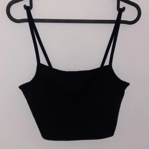 Svart ärmlös linnetopp - Snygg svart ärmlös linnetopp med smala axelband. Perfekt för sommardagar eller som ett basplagg i garderoben. Enkel och stilren design som passar till det mesta.