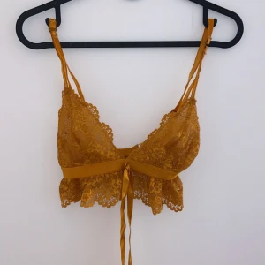 Gul spetslinnetopp - Säljer en superfin gul spetslinnetopp med smala axelband och knytning fram. Perfekt för sommardagar eller festliga tillfällen. Toppen är i ett lätt och luftigt material som känns bekvämt mot huden.