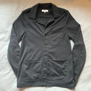 Svart overshirt från Studio Total - Snygg svart kavaj från Studio Total i storlek XS. Den har en klassisk design med knappar framtill och flera praktiska fickor. Perfekt för en stilren look. Tröjan är i väldigt bra skick. Bara att skicka om man har några frågor🤗👌