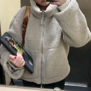 Beige teddyjacka med dragkedja - Mysig beige teddyjacka med dragkedja framtill. Jackan har en oversized passform och långa ärmar, perfekt för kyliga dagar. Den fluffiga texturen ger en trendig look.