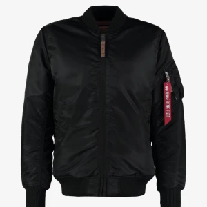 Bomberjacka - Snygg svart bomberjacka från Alpha Industries med ikonisk röd 'Remove Before Flight'-tag. Jackan har ett orange foder och dragkedja framtill. Nypris 2279kr. Storlek M passar XS, S.