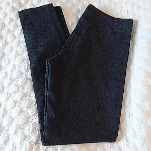 Svarta leopardmönstrade byxor från H&M - Snygga svarta byxor från H&M med ett diskret leopardmönster. Perfekta för att ge din outfit en trendig touch. De är stretchiga och bekväma, vilket gör dem idealiska för både vardag och speciella tillfällen.