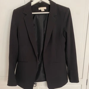 Svart kavaj från H&M - Snygg svart kavaj från H&M med klassisk design. Den har långa ärmar och en stilren passform 🖤