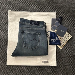 Jacob Cohen jeans - Snygga blå jeans från Jacob Cohen med en klassisk femficksdesign. De har en diskret tvättad look och är tillverkade av högkvalitativt denim. Perfekta för en stilren och avslappnad stil. Fint skick. Lite minimala defekter som syns på bilderna. Dammodell men passar även killar bra. Storlek: 31 Nypris: 5000kr Mitt pris: 999kr OBS: Framfickorna är väldigt små, iprincip icke funktionella. 