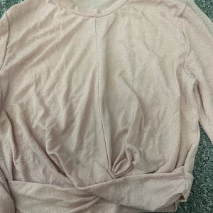 Rosa glittrig tröja - Säljer en rosa glittrig tröja från H&M med långärmad design och en snygg knutdetalj framtill. Perfekt för att lägga till lite glitter i vardagen. Passar bra till både jeans och kjol. ( på andra bilden ser man färgen på tröjan mycket bättre). Passar snarare S eller M