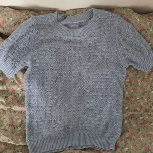 Ljusblå stickad tröja - Säljer en ljusblå stickad tröja med korta ärmar och ett fint hålmönster. Perfekt för vår och sommar. Tröjan har ribbade kanter vid hals, ärmslut och nederkant.🫶🏼🌸 Storlek XS och säljer pga att den inte kommer till användning, men så söt!!