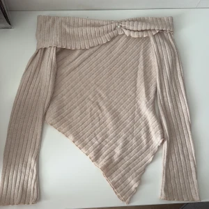 Beige ribbad offshoulder topp - Säljer en snygg beige ribbad offshoulder topp med asymmetrisk design. Toppen har långa ärmar och en dekorativ pärldetalj framtill. Perfekt för en trendig look! Den är i storlek M men passar bra för mig som har S vanligtvis, pris kan diskuteras 🌸
