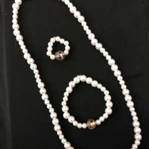 Pärlhalsband och armband med kristalldetalj - Elegant set med ett pärlhalsband och ett matchande armband. Båda smyckena har vita pärlor och en iögonfallande kristallpärla i mitten som ger en lyxig touch.