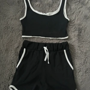 Svart croppad linnetopp med vita kanter - Snygg svart croppad linnetopp med kontrasterande vita kanter. Perfekt för en avslappnad stil. Matcha med shorts eller jeans för en cool look.