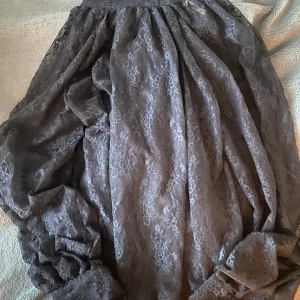 Svart spetsblus med rosett i nacken från H&M - Elegant svart spetsblus från H&M med långa ärmar och en vacker knytning i halsen. Perfekt för en stilfull look med sitt fina spetsmönster. helt oanvänd bara att lappen är borttagen 