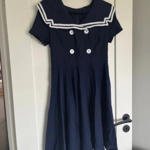Sjömansklänning strl M - Snygg sjömansklänning, inköpt i ”rockabillybutik” men minns inte märke. Aldrig använd. Strechigt material. Klockad kjol, knälång.