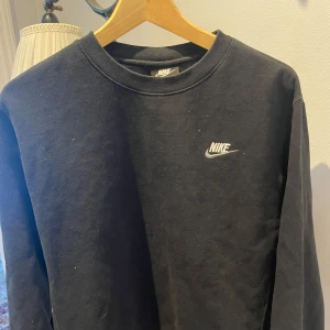 Svart långärmad tröja från Nike - Säljer en stilren svart långärmad tröja från Nike med deras klassiska logga på bröstet. Perfekt för en avslappnad look. Tröjan är i storlek S och har en bekväm passform.
