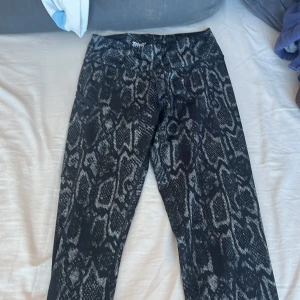 Svarta leggings med mönster från Crivit - Snygga svarta leggings från Crivit med ett coolt mönster som påminner om ormskinn. Perfekta för en trendig look och bekväma att bära. Passar bra till både träning och vardag.