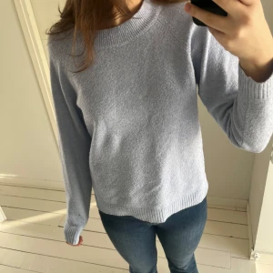 Ljusblå stickad tröja - Säljer en mysig ljusblå stickad tröja med rund hals och långa ärmar. Perfekt för kyligare dagar och lätt att matcha med jeans eller kjol. Tröjan har ribbade muddar vid ärmslut och nederkant för en bekväm passform.