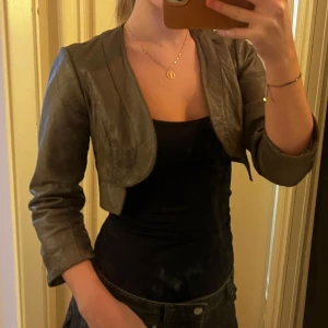 Läderbolero - Snygg brun bolero med quiltad design och trekvartsärm. Jackan är croppad och har en stilren look utan knappar eller dragkedja. Perfekt för att ge en edgy touch till din outfit.