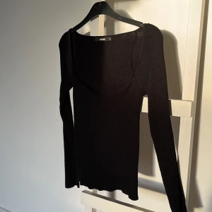 Svart ribbad topp från Bik Bok - Snygg svart ribbad topp från Bik Bok med långärmad design och en stilren v-ringning. Perfekt för en chic och enkel look.