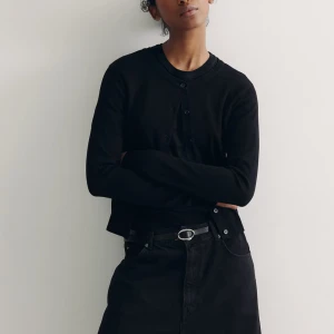 Svart kofta med knappar - Snygg och stilren svart kofta med knappar framtill. Perfekt för lager-på-lager och passar till många olika outfits. Den har långa ärmar och en klassisk rund halsringning.